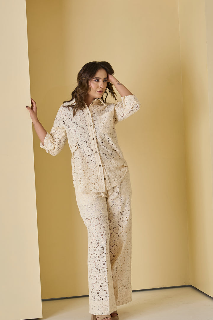 Woman wearing a beige lace outfit against a beige wall