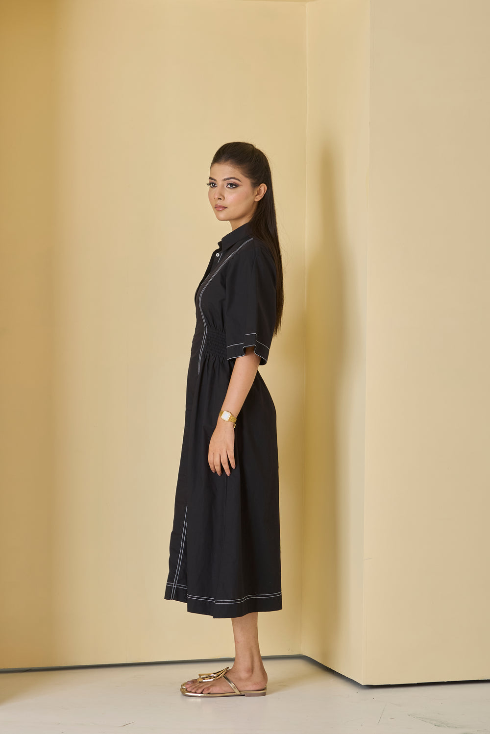 Woman wearing a black dress standing against a beige wall
