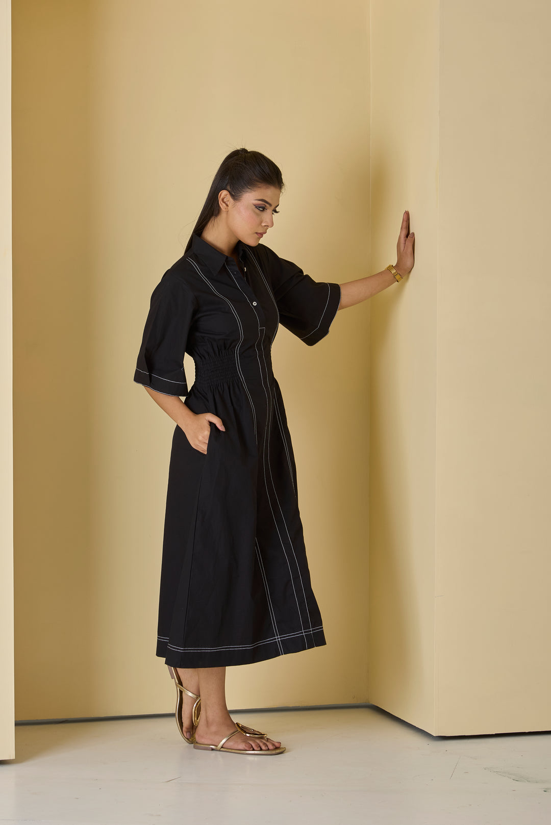 Woman wearing a black dress against a beige wall