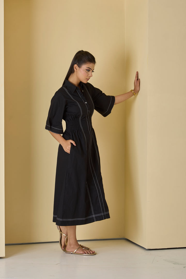 Woman wearing a black dress against a beige wall
