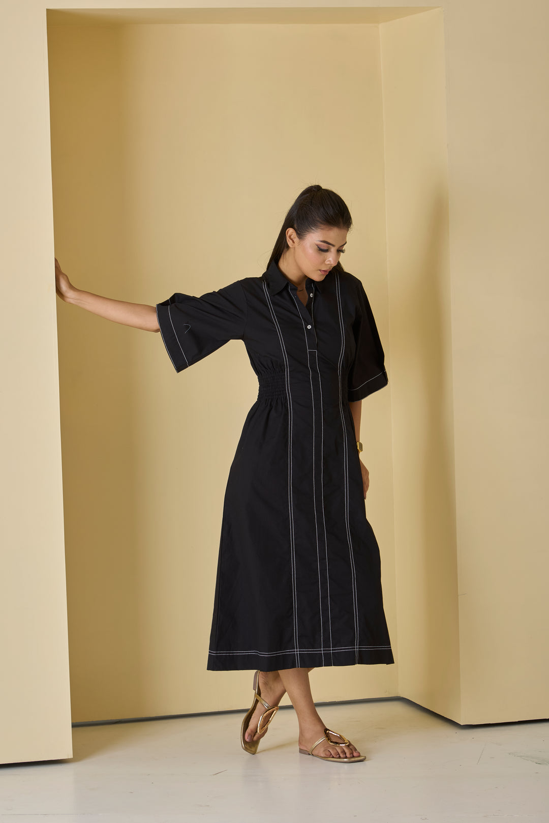 Woman wearing a black dress with white stripes in a minimalistic setting