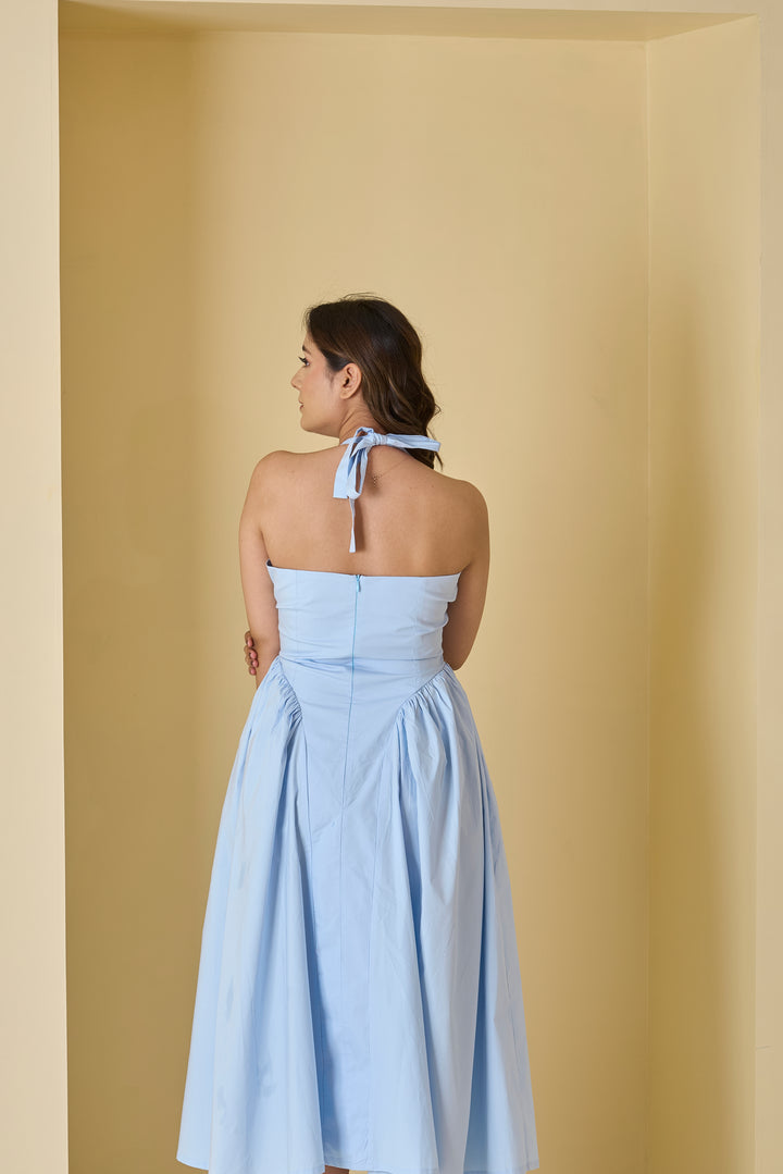 Woman wearing a light blue dress against a beige wall