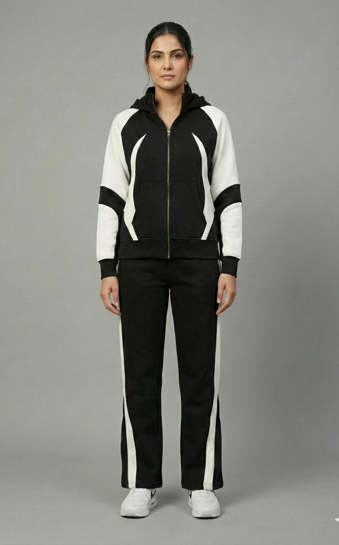 Woman wearing a black and white tracksuit on a gray background