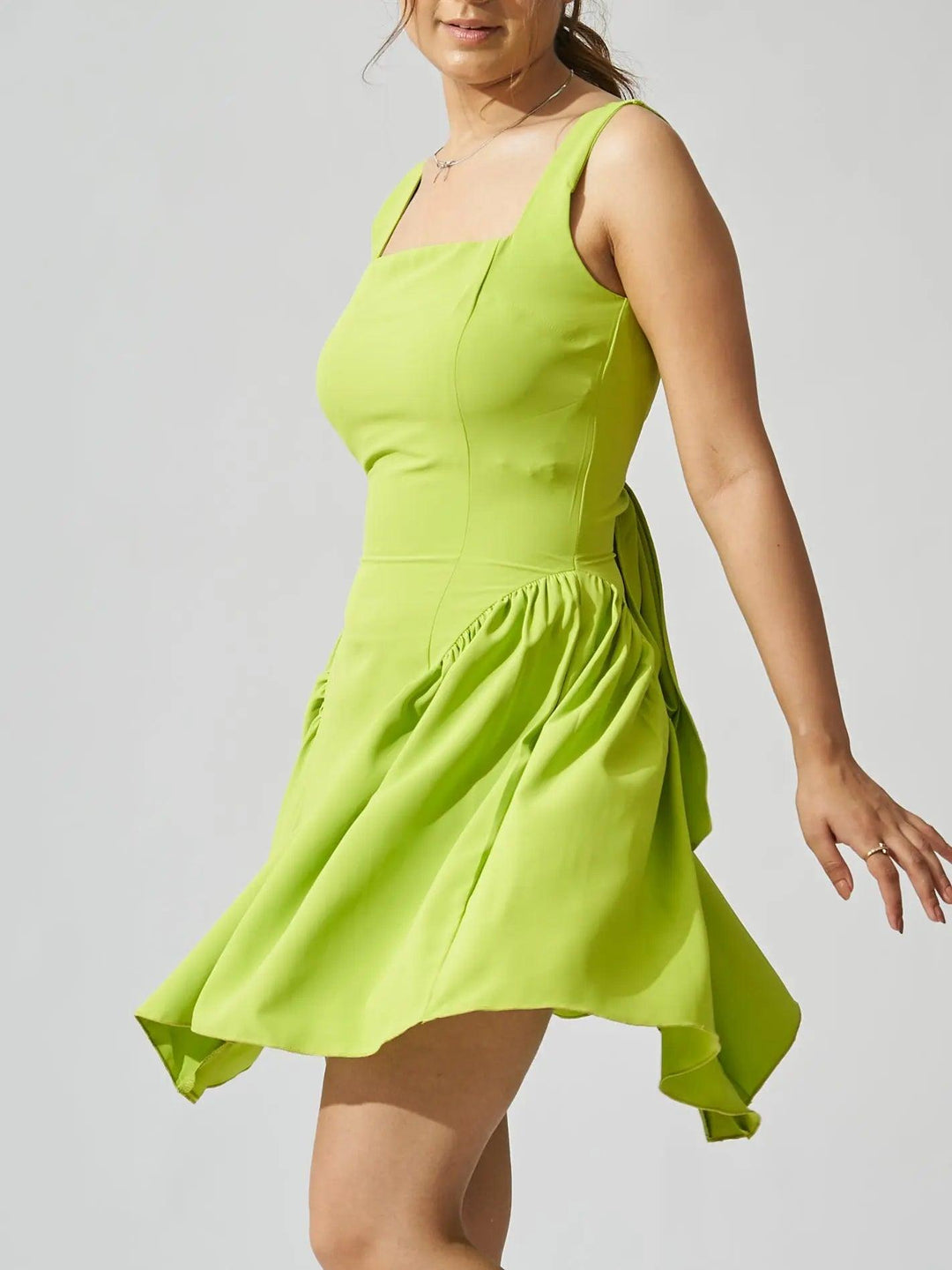 Risate backless bow mini dress in vibrant green with playful flared hem and elegant silhouette