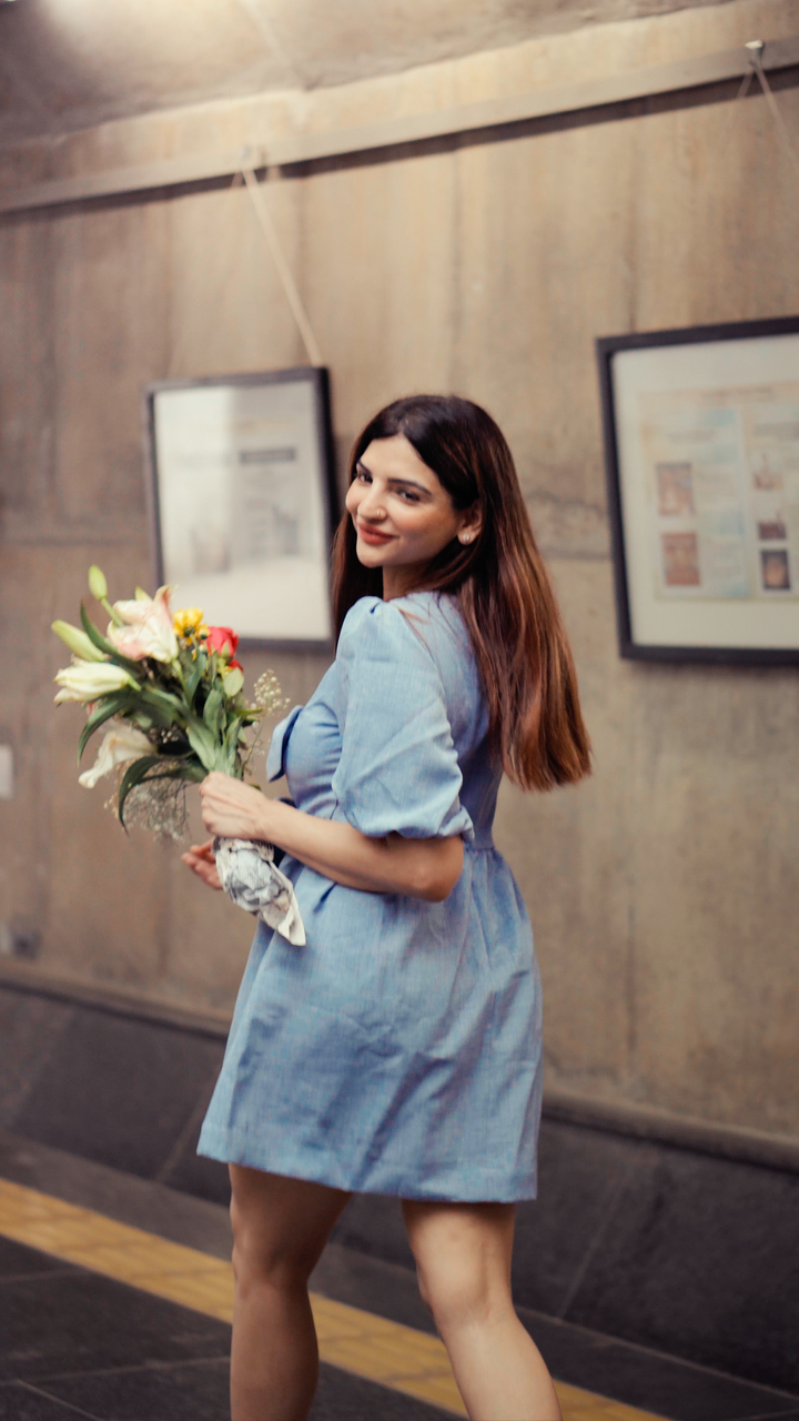 Risate blue mini dress worn by woman holding bouquet of flowers in urban setting