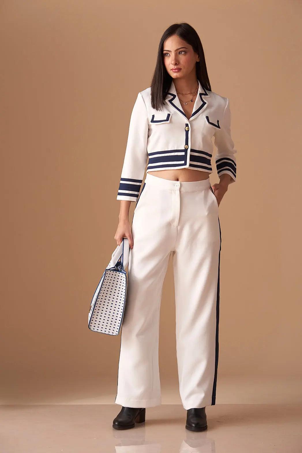 White Risate co ord set featuring a cropped jacket and wide-leg pants with navy stripes and a stylish handbag