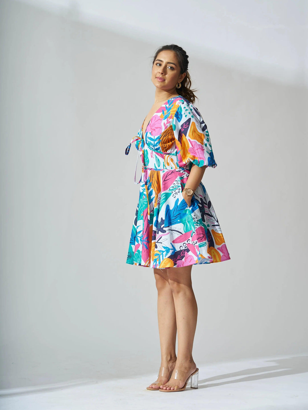 A woman wearing a coral reef linen dress with a vibrant floral print and short sleeves
