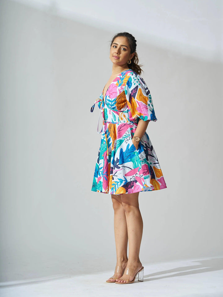 A woman wearing a coral reef linen dress with a vibrant floral print and short sleeves