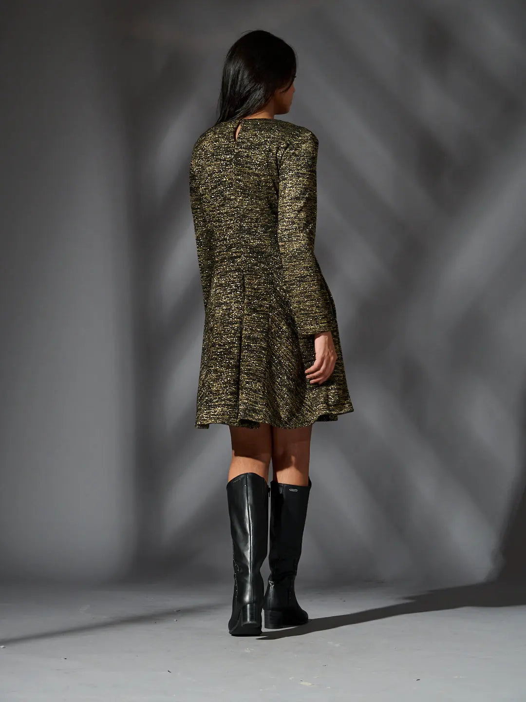 Back view of a Risate golden knit glam dress with a flared skirt and long sleeves