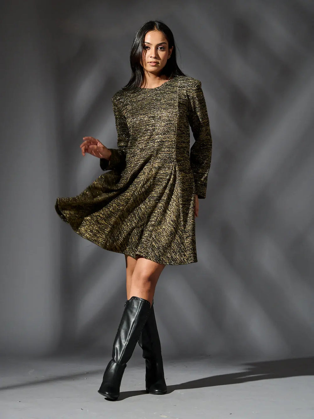 Woman twirling in a golden knit glam dress featuring a stylish design and flattering fit