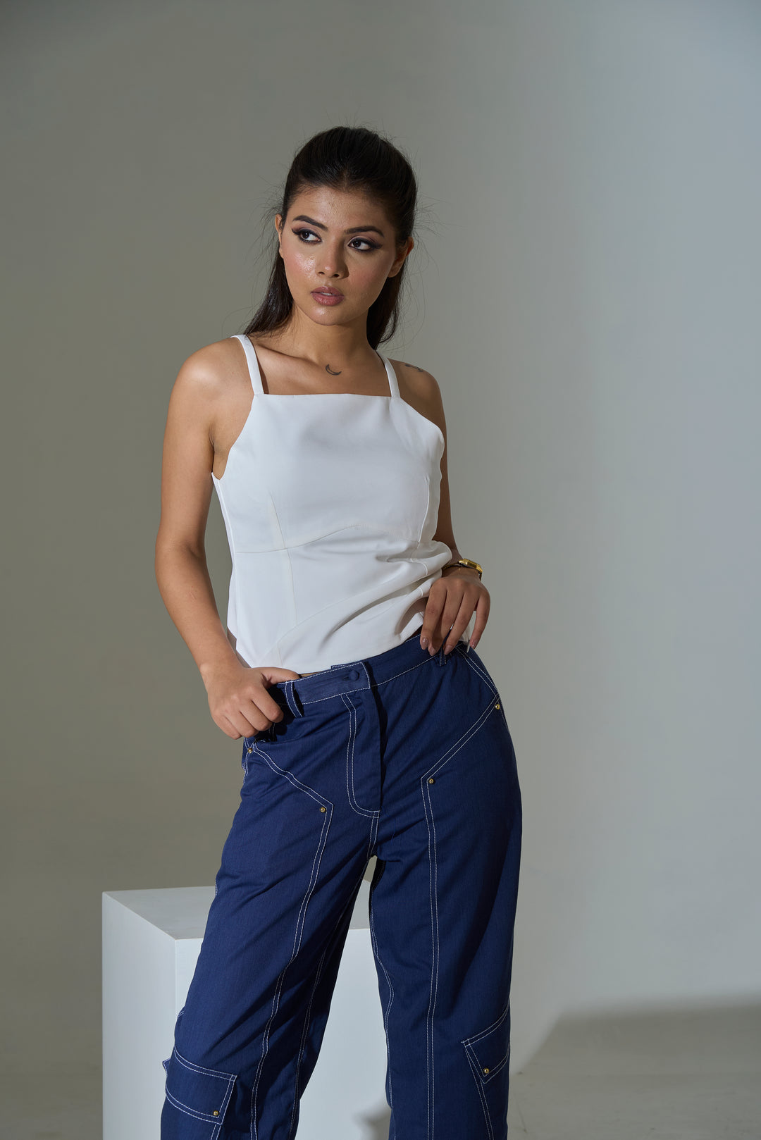 Model wearing an ivory bow-back cami top paired with stylish blue pants for a chic look