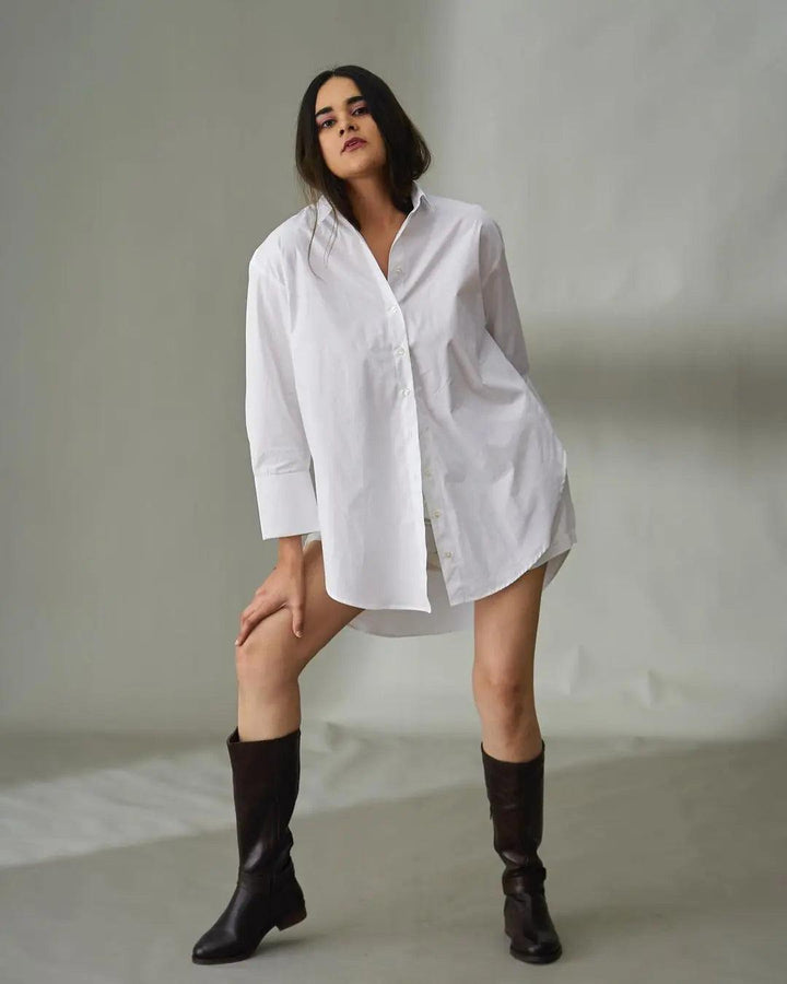 Model wearing an oversized poplin shirt for women, styled with knee-high boots for a chic look