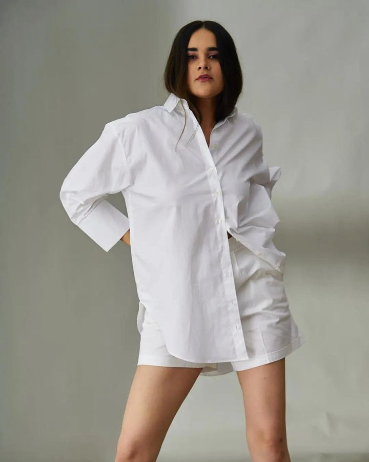 Model wearing a white oversized poplin shirt for women styled with shorts