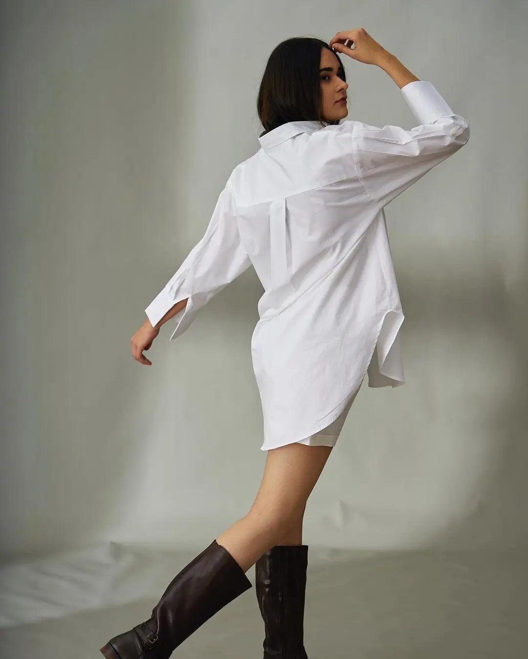 Model wearing an oversized poplin shirt for women in white, paired with stylish knee-high boots