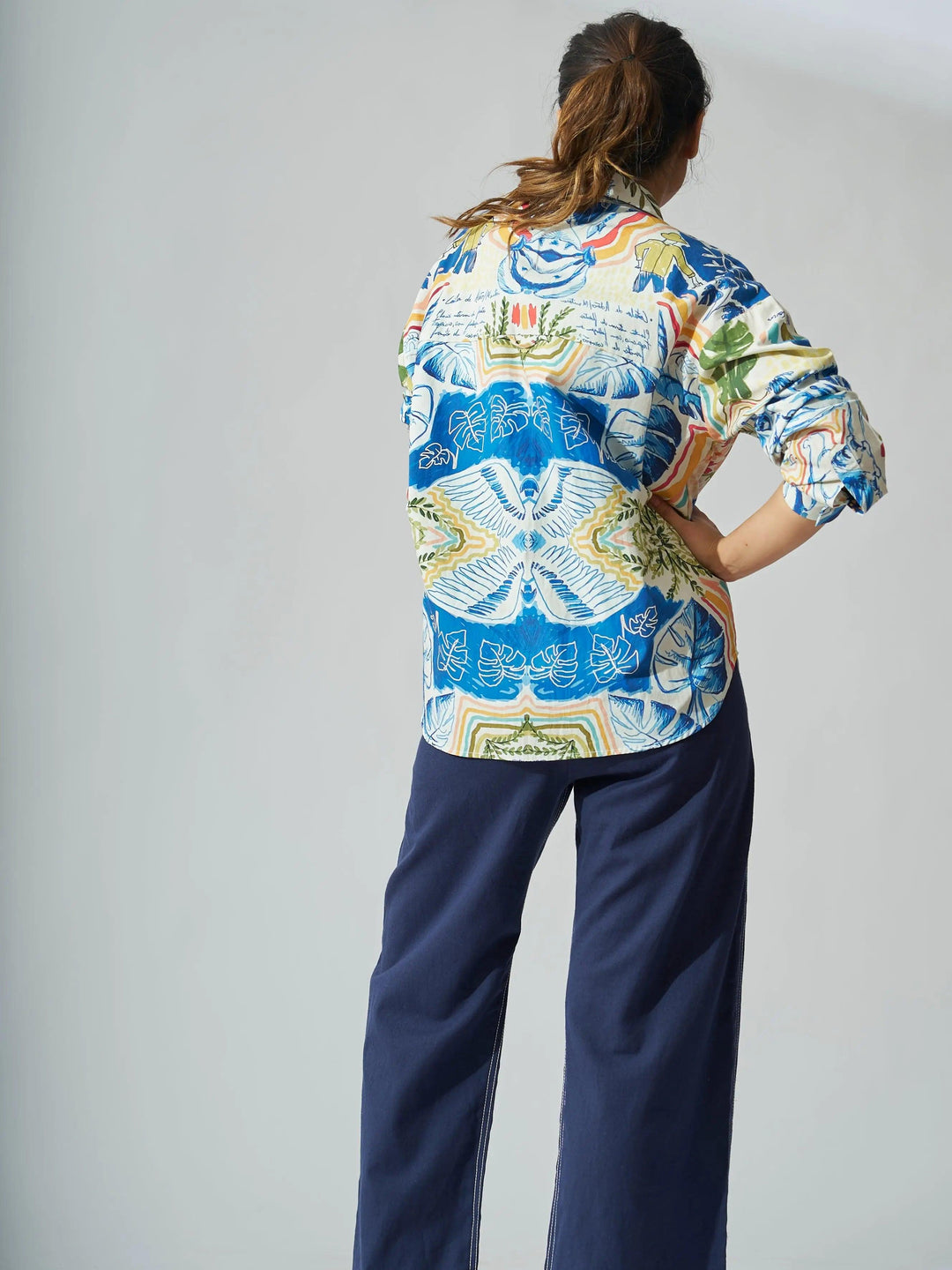 Colorful personage print cotton shirt for women displayed from the back, paired with navy pants