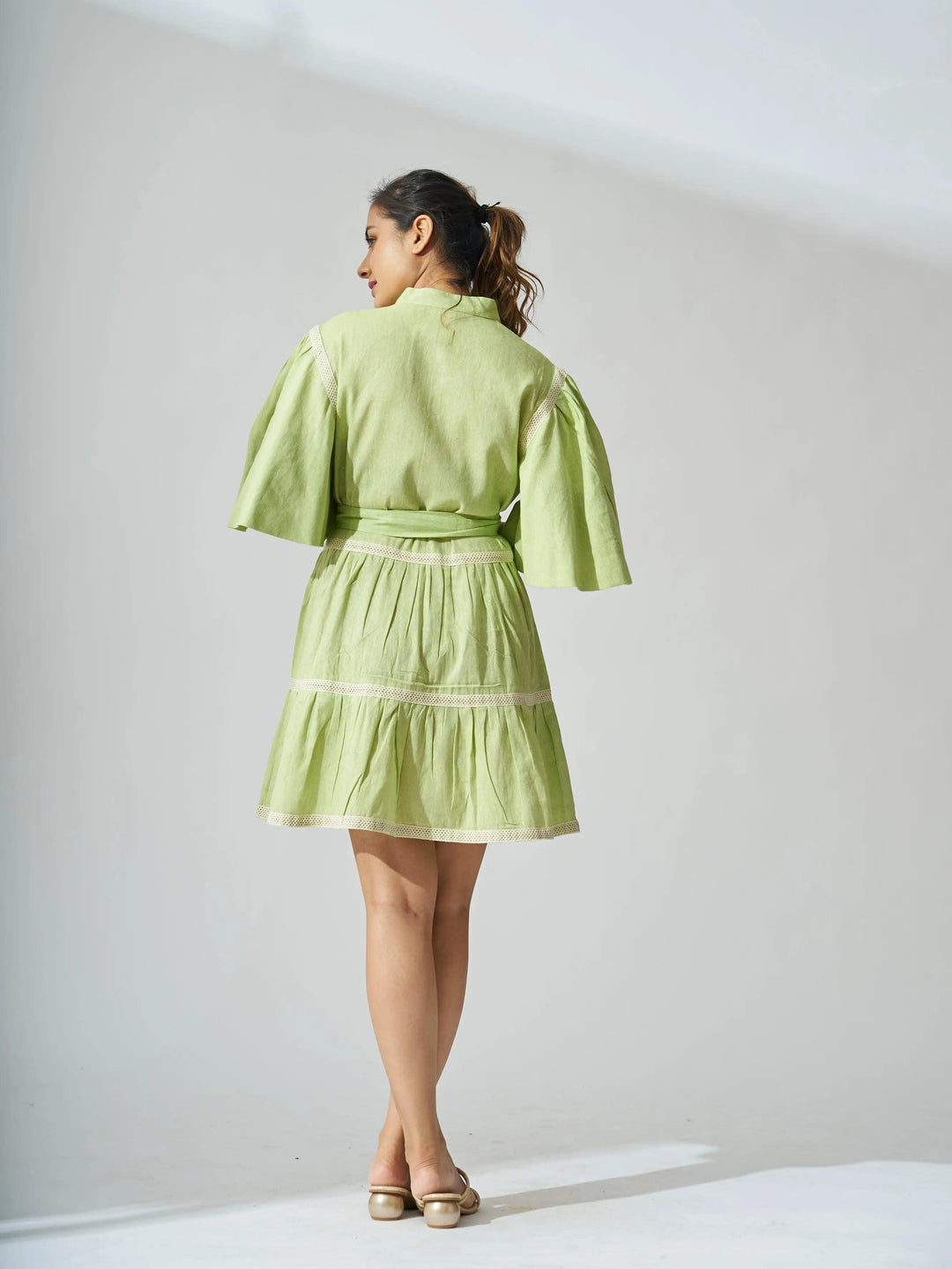 Back view of a light green ruffle linen blend mini dress with balloon sleeves and a cinched waist