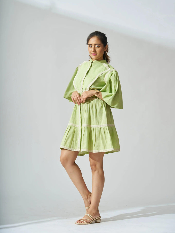 Model wearing a light green ruffle linen blend mini dress with short sleeves and tiered design