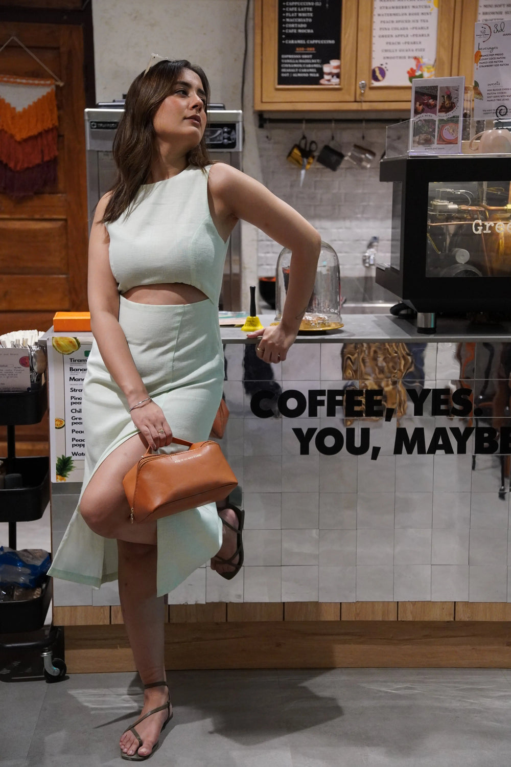 Sage cut out dress by Risate showcasing a stylish design in a cafe setting