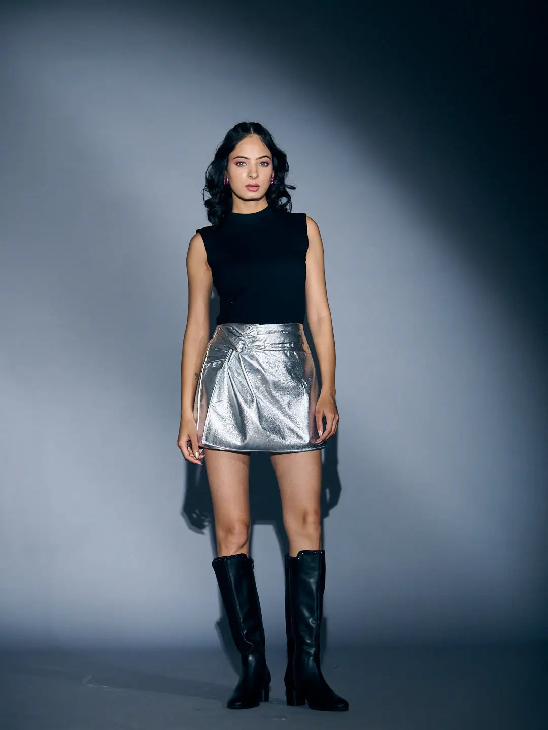 Stylish silver skort for women with a flattering high-waist design, paired with a black top and knee-high boots