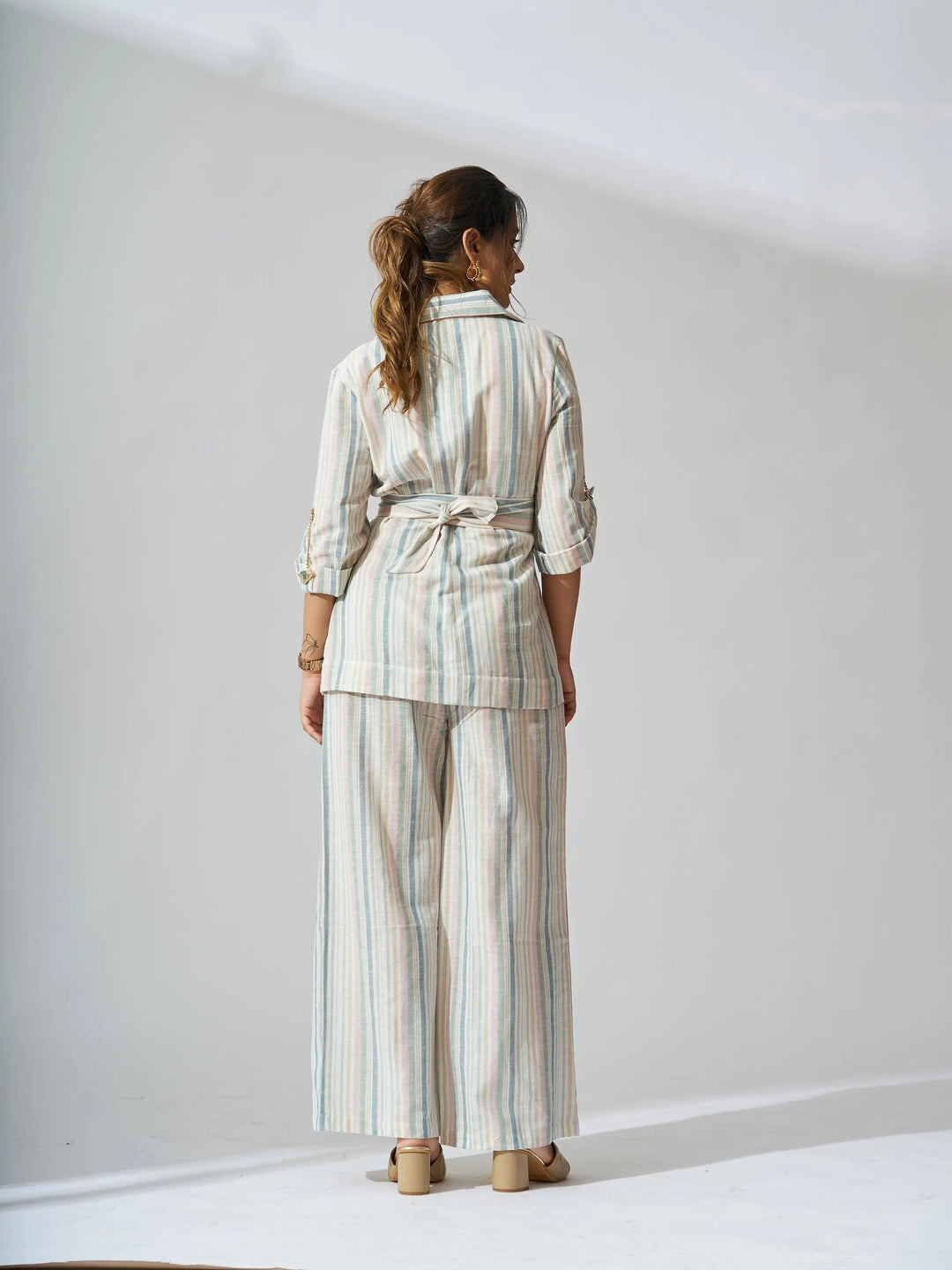 Back view of women's striped linen blazer set by Risate styled with wide-leg pants