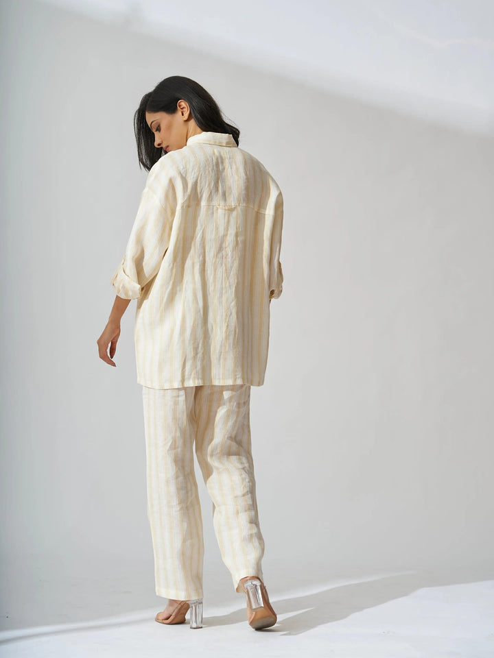 Back view of a woman wearing a yellow stripes linen coord set for women, featuring a loose-fitting shirt and trousers
